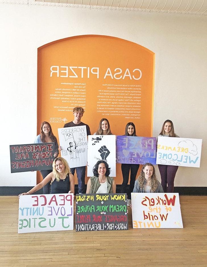 students pose in front of the casa sign with protest posters